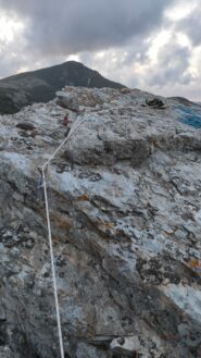 Cima: corda fissa e anello di calata collegato con cordino viola in loco.